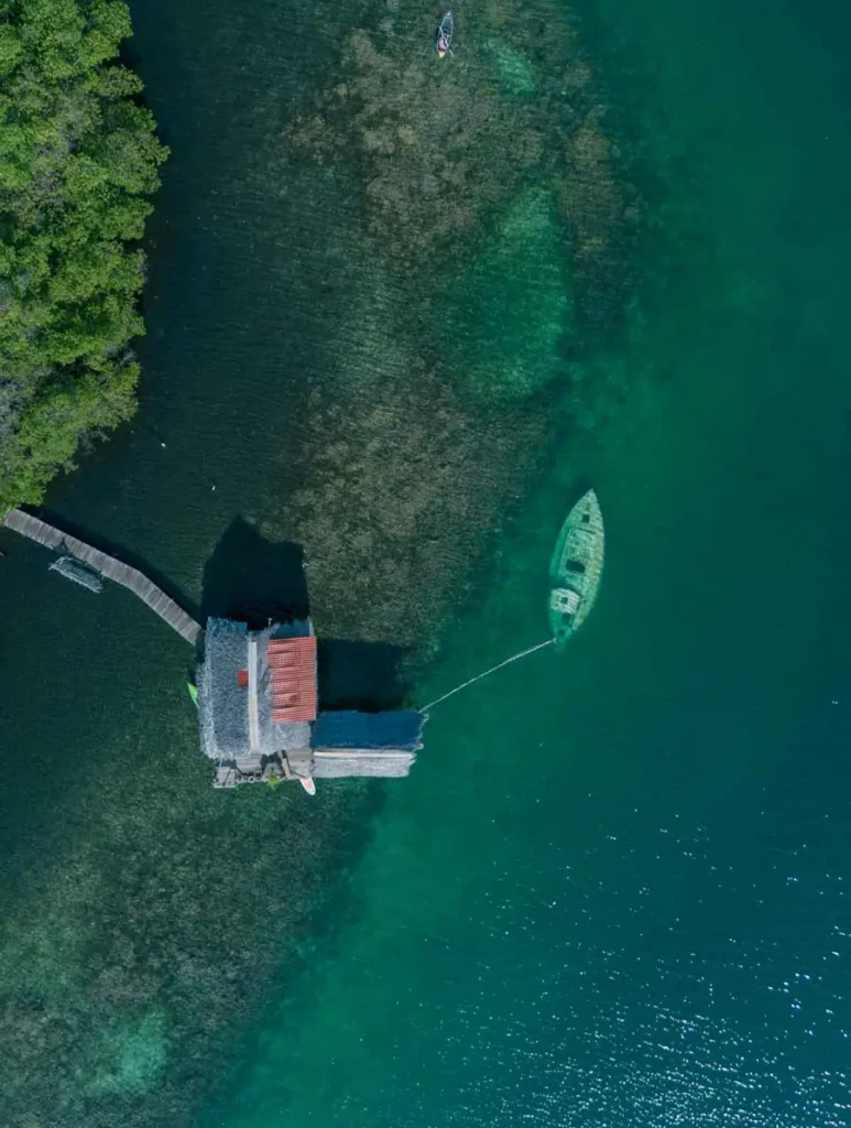 cover best things to do in Panama birds view image of an overwater bungalow above a coral reef with a sunken boat