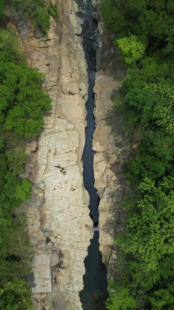 birds eye view of a narrow rock canyon with a river flowing through it and lush vegetation around
