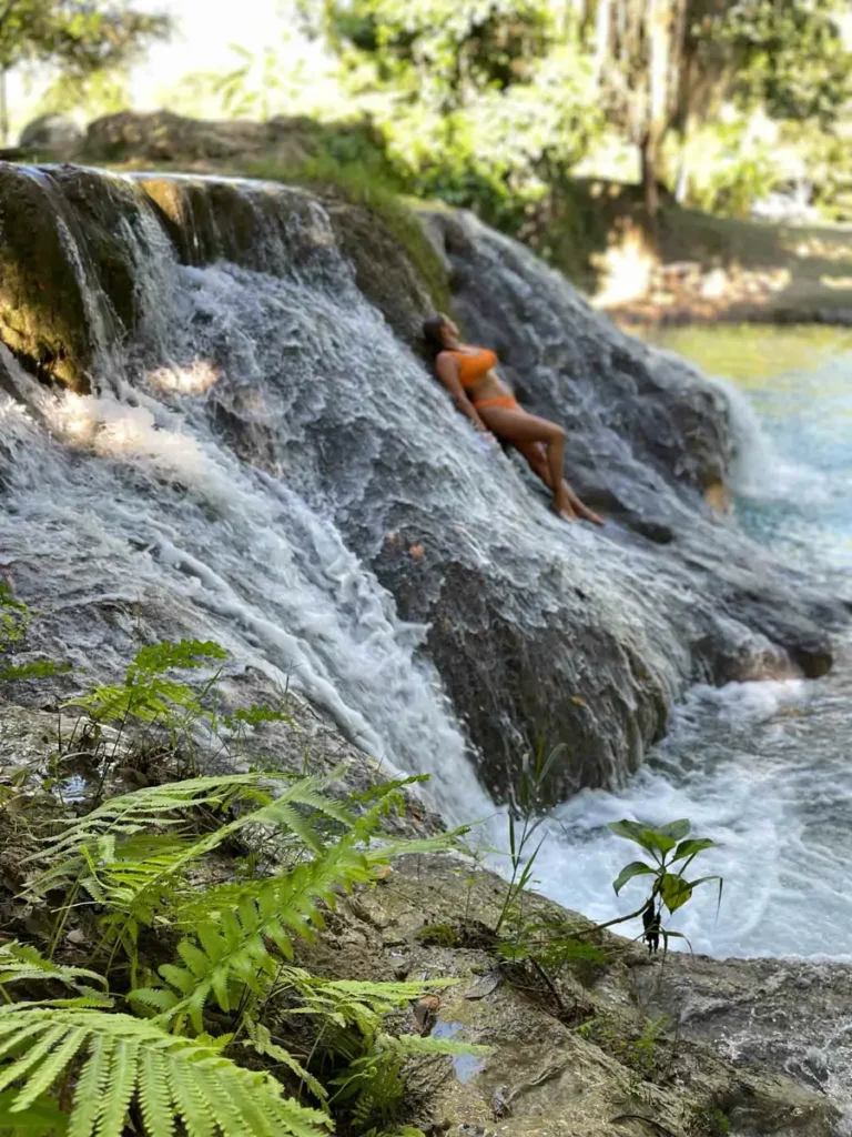 woman laying on a wide waterfall surrounded by a forest or jungle nature in Mexico, ideal for the perfect Mexico itinerary