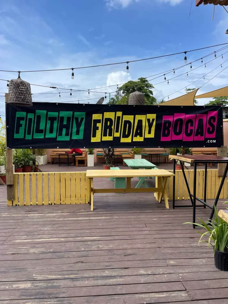 large black banner with colourful letters on a wooden terrace with some table and light bulbs hanging above in bocas del toro in panama