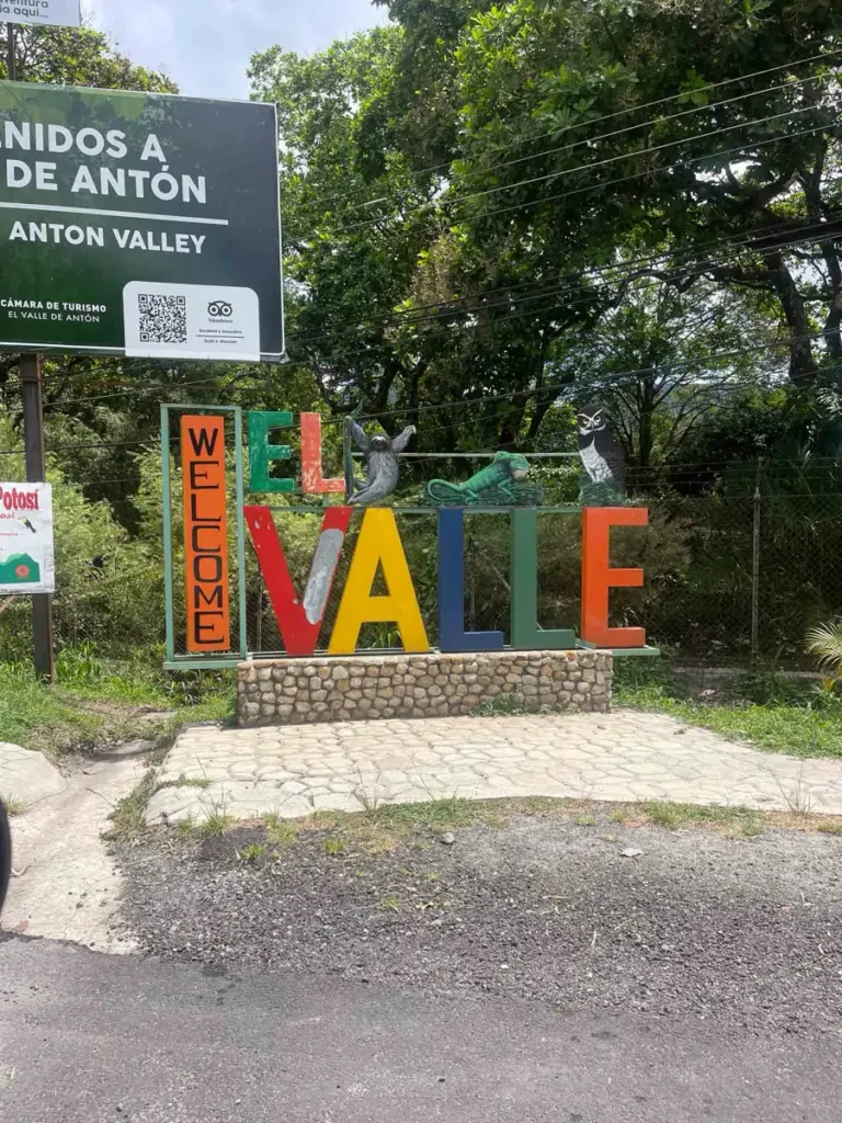 colourful signs with the town name and a sign post in the background + lush greenery