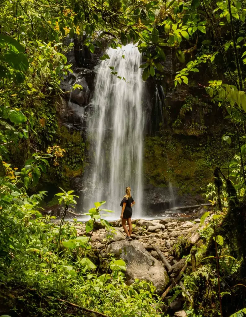 cover epic hikes in Panama woman standing in front of a large waterfall in the jungle surrounded by greenery