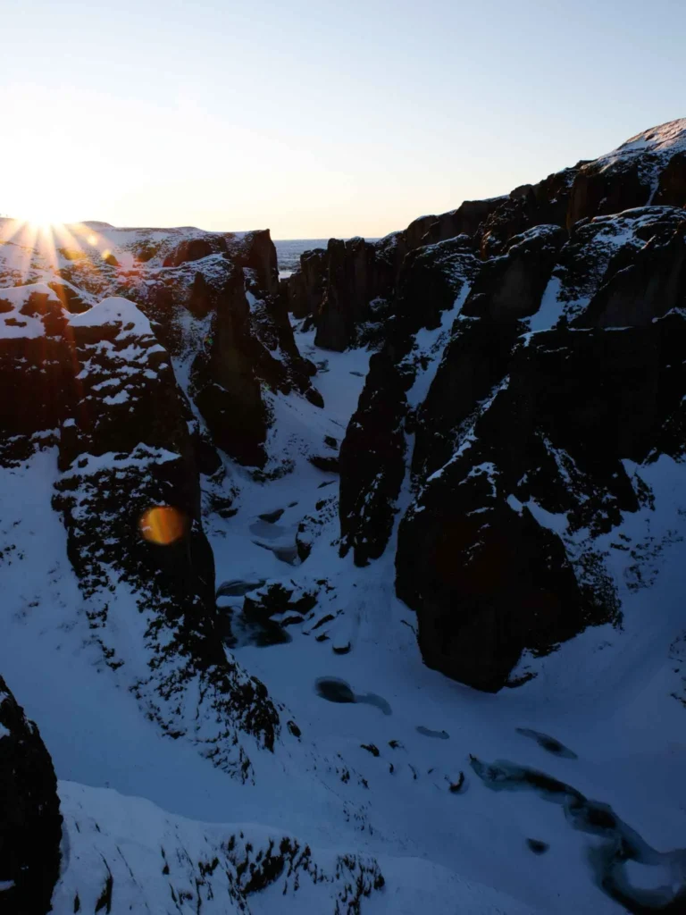 rocky terrain with snow with a low sun at fjadrargljufur in iceland