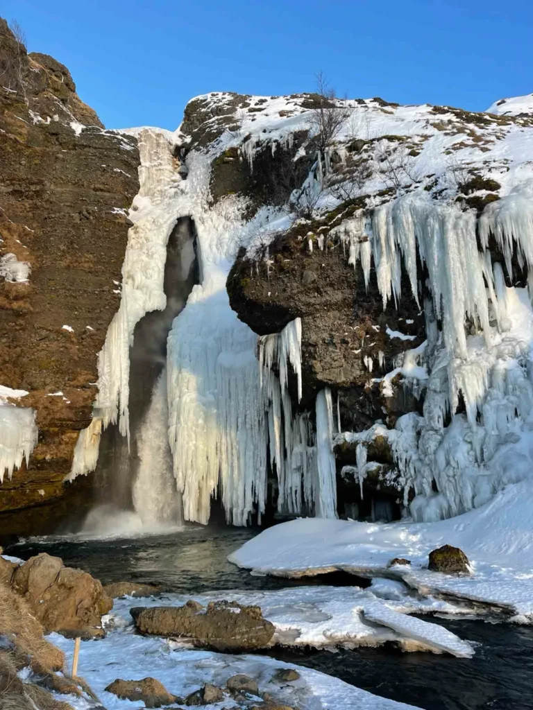 Gluggafoss waterfall rocky terrain with the frozen gluggafoss waterfall and ice spikes hanging along the rocks in iceland
