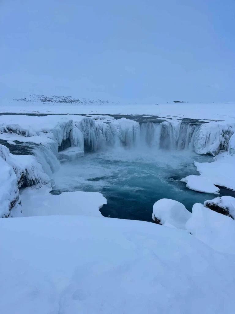 partially frozen wide waterfall godafoss in a snowy landscape in iceland
