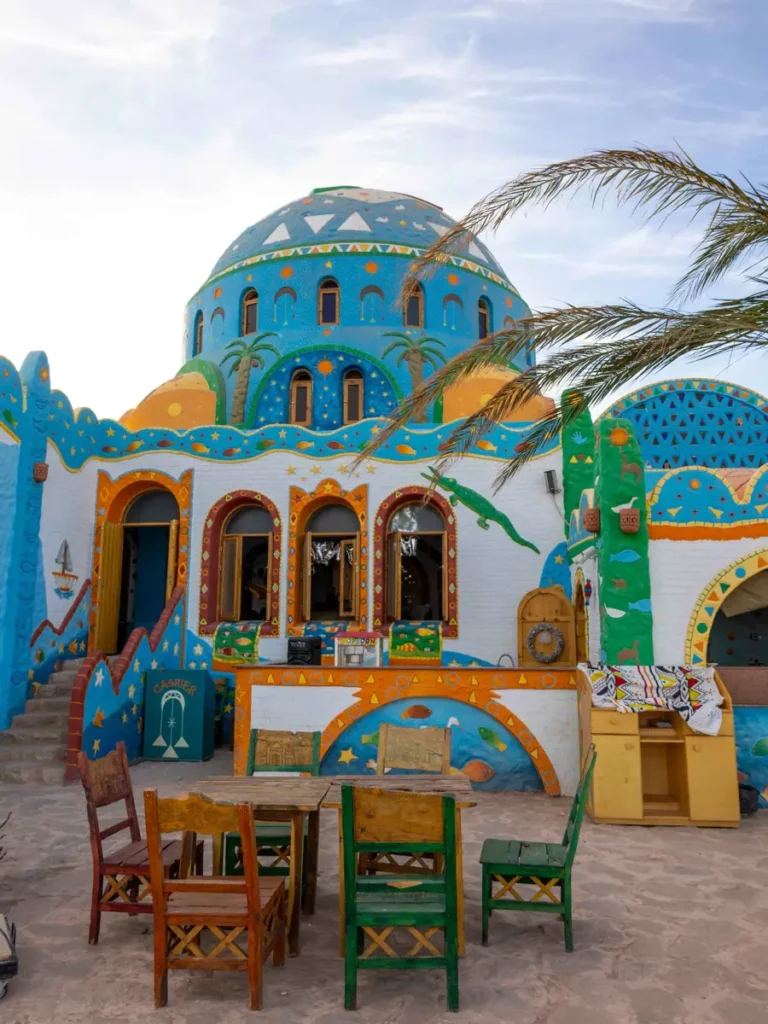 colourful round house with lots of decorations and a palmtree in front