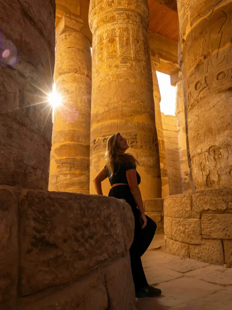 woman looking at the impressive columns at an ancient temple, sunrays coming through