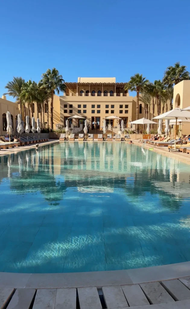 large hotel pool with many sunbeds and palmtrees