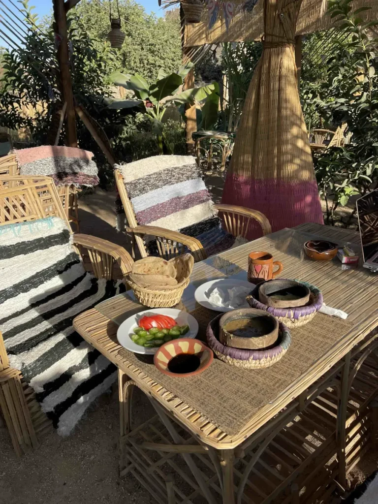 table with typical Egyptian dinner with multiple plates and two chairs with colourful pillows