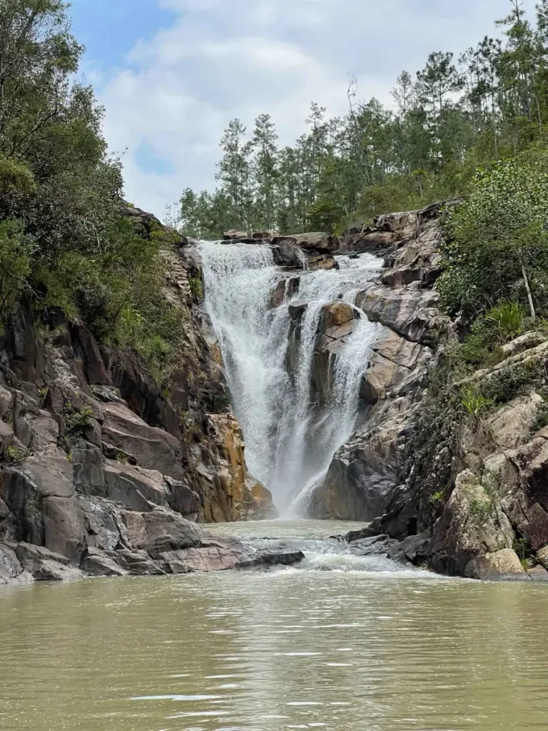 waterfall with a body of water surrounded by rocks and a pine forest at mountain pine ridge reserve in belize