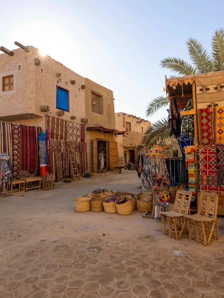 colourful carpets and other goods in a traditional mud house with the sun peaking over the edge