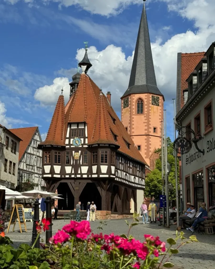 Beautiful traditional city hall with half-timbered architecture and a church in the background in the storybook town of Michelstadt in Germany