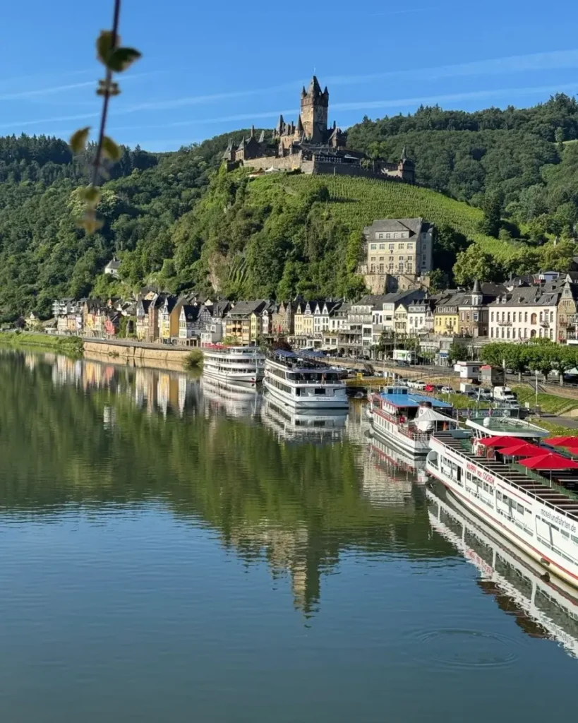 View of a stunning river-side town with a castle on a hill and colourful houses in Cochem, Germany and a perfect reflection in the water