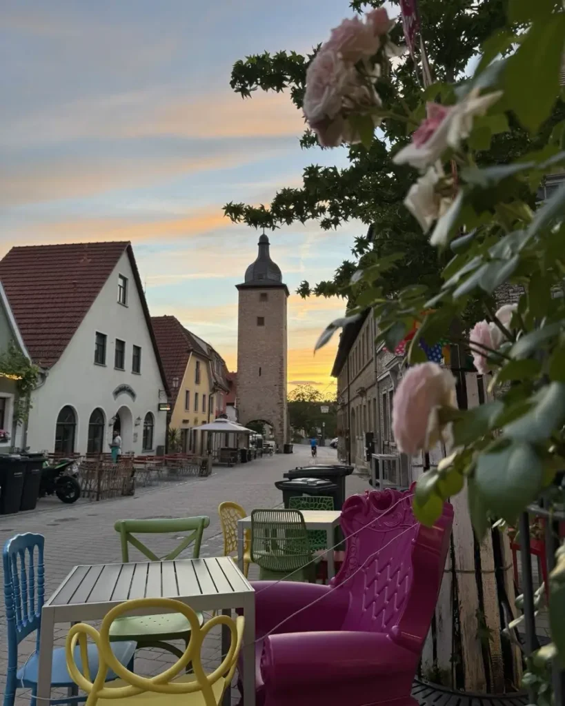 Colourful sunset in a charing town with a historic tower, beautiful houses, roses and colourful outdoor seating area in Volkach am Main