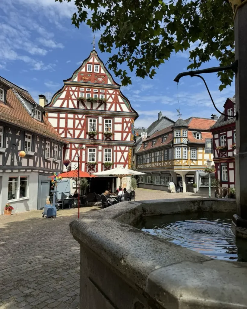 Fountain below a tree with beautiful half-timbered houses and cobblestone roads in the Idstein, Germany