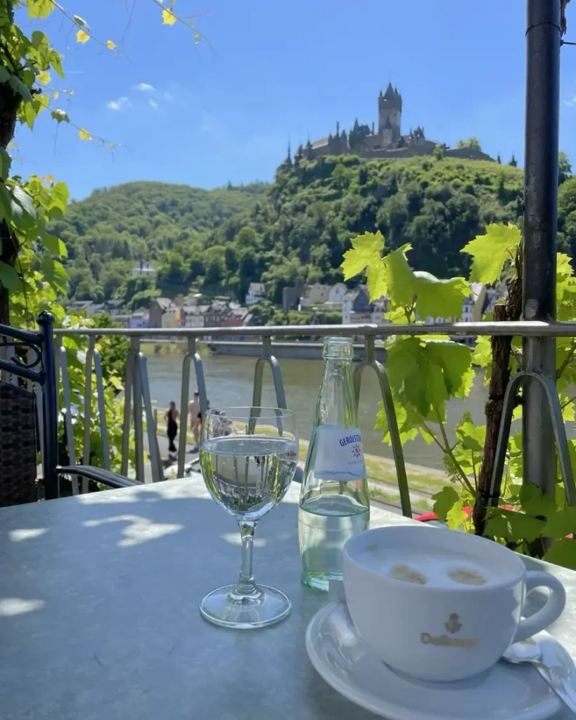 view from a table at a café of a stunning riverside fairytale town in Germany, Cochem with coffee and sparkling water on the table
