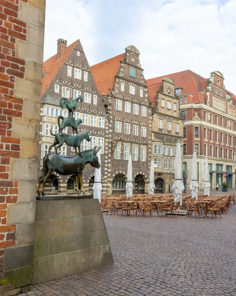 Statue of the 4 Bremer town musicians with traditional houses with high roofs in the background in Bremen, germany
