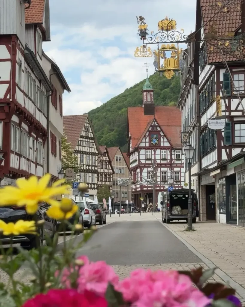 A beautiful town with half-timbered houses, a golden traditional sign and flowers in the foreground in Bad Urach, Germany