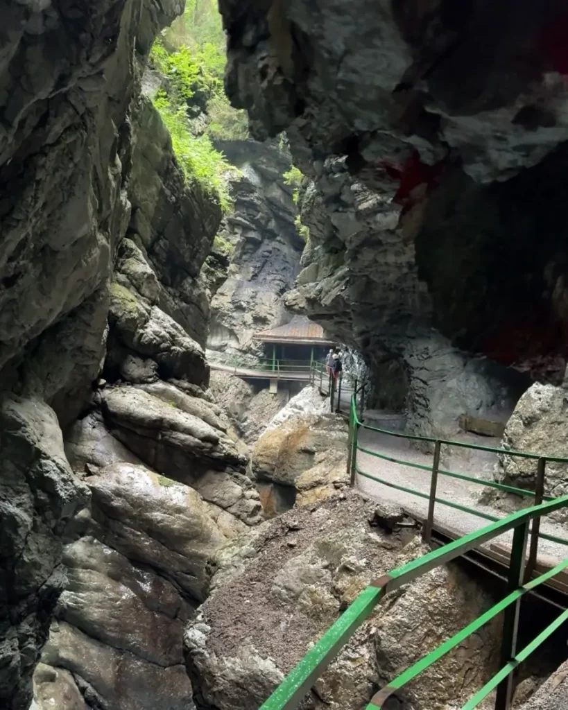 Impressive gorge with massive rock walls on both sides with a walkway with greeen handle and a small hut in the distance: Breitachklamm