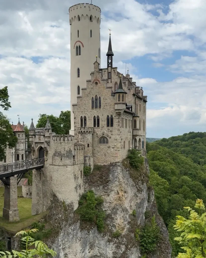 Impressive Lichtenstein Castle built on top of a large rock and connected to the hill by a brige with greenery in the surroundings