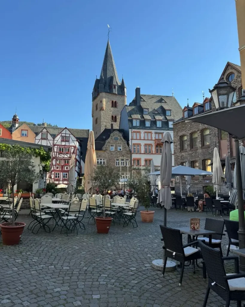 Old town square with outdoor seating areas, cobblestone roads, a church and traditional houses in the fairytale town of Bernkastel-Kues