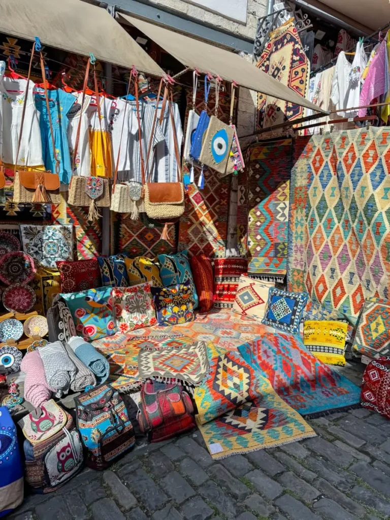 local store with colourful clothes, carpets, bags and more in Gjirokastër - a must stop on your Albania itinerary