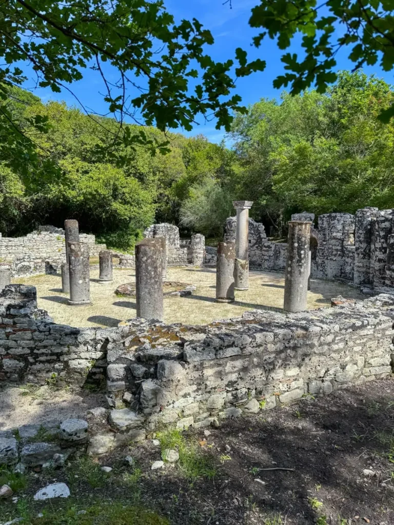 Archeological ruins of a temple with multiple stone walls and columns surrounded by trees in Butrint Archaelogical National Park, Albania