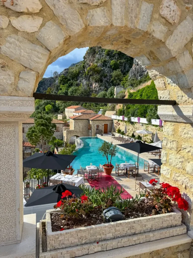 Arched window view in a stone building at Zoe Hora hotel in Albania with view of a restaurant area and pool