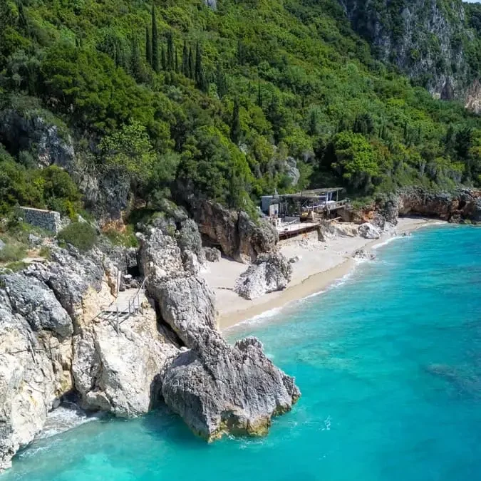 bird's eye view of a beach with large rocks, white sand and lush vegetation