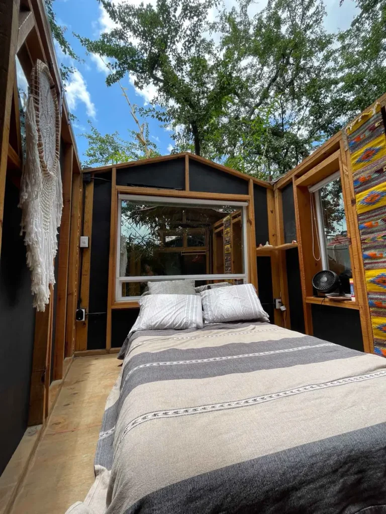 you can open the roof of this unqiue treehouse im Oaxaca! bed inside a small wooden cabin or tree house with a roof that can be opened looking at trees and the blue sky at Huamuchil treehouse in Oaxaca City