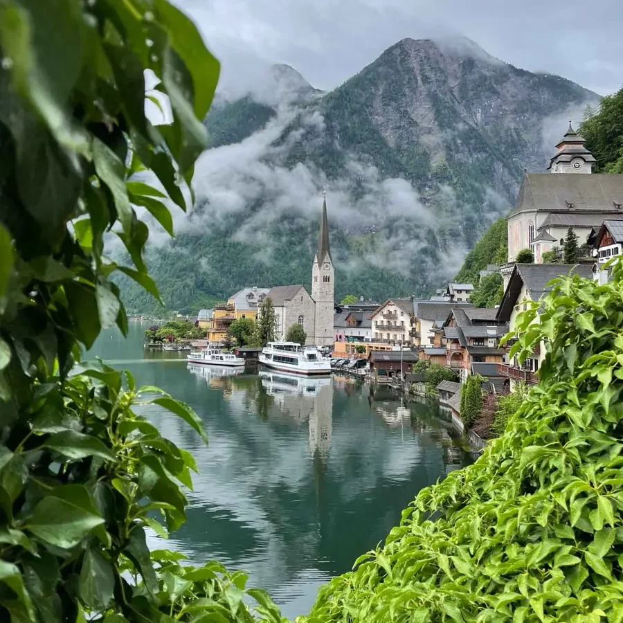 lakeside town with a beautiful church, reflection, mountain backdrop and greenery in the foreground of the image