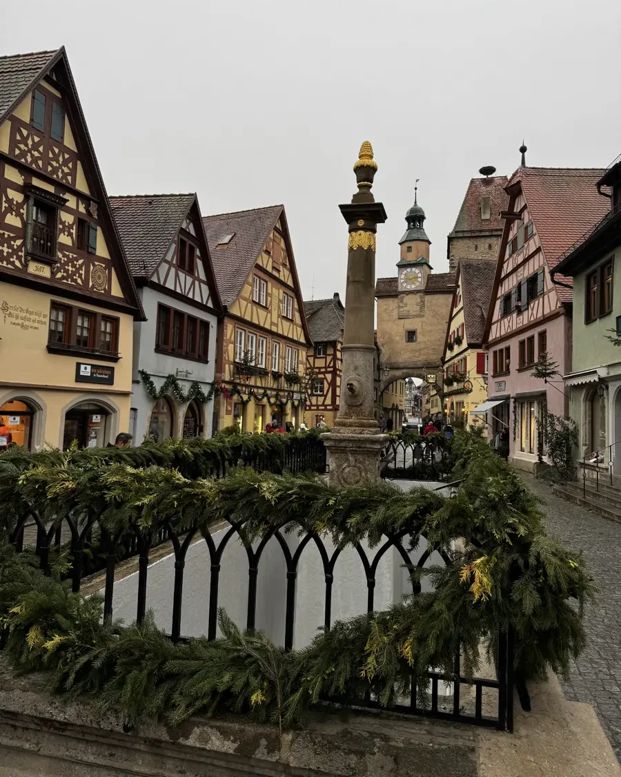 Historic fountain with christmas decorations in the medival town of Rothenburg ob der Tauber with traditional houses and a gate
