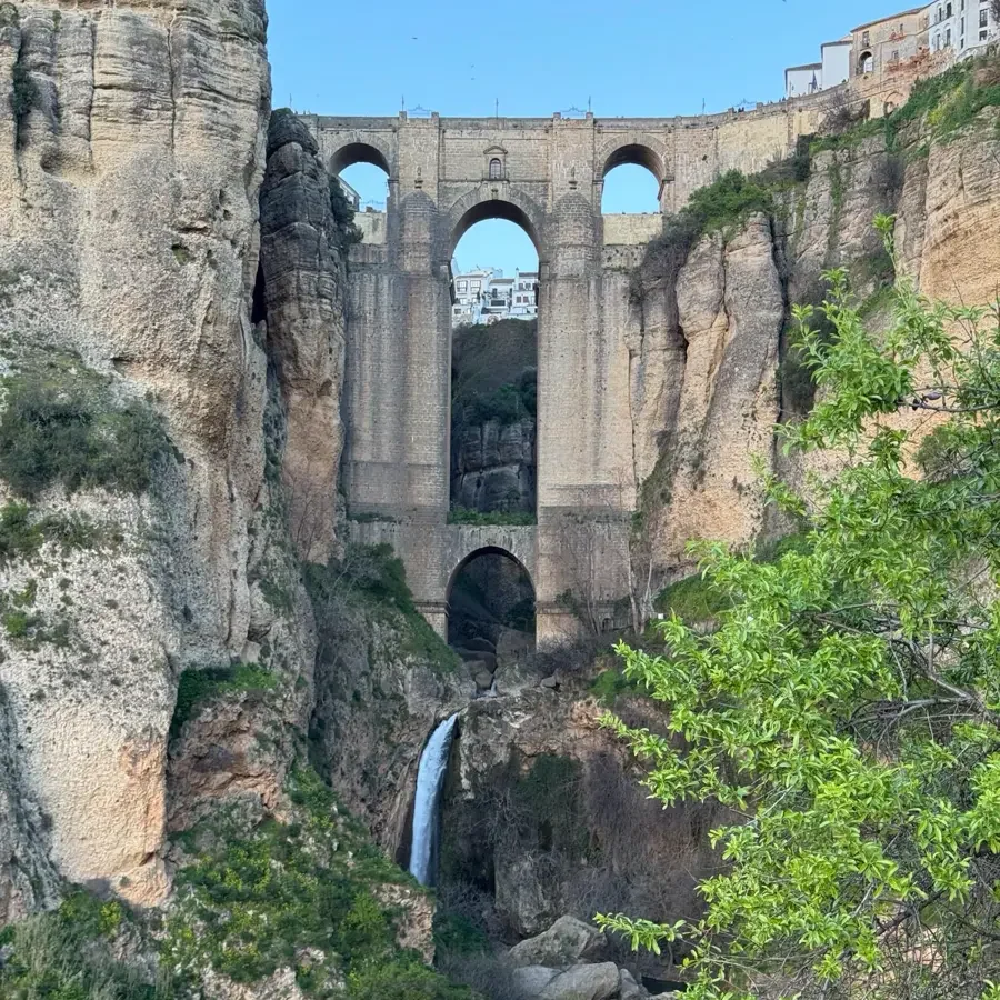 impressive bridge over a gorge with a waterfall, rocks and green vegetation