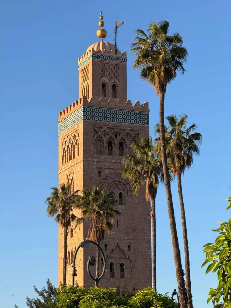 tower of a mosque hit by golden light before sunset with blue skies and palmtrees