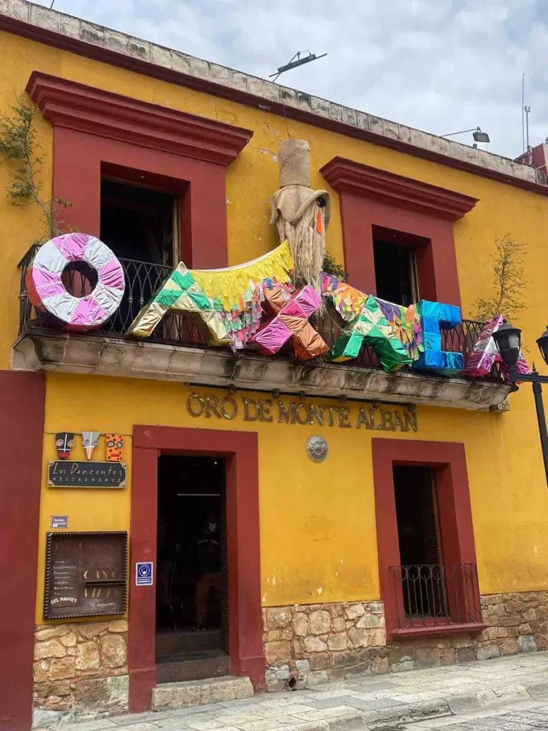 yellow and red/brown house with a few pinatas writing out oaxaca in Oaxaca City in Mexico