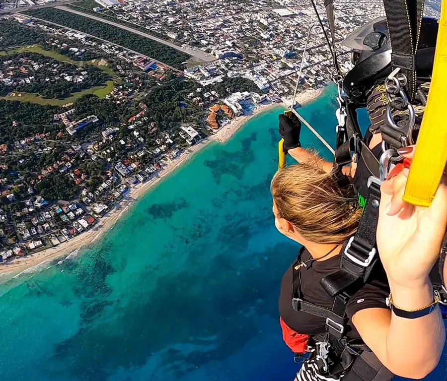 blonde woman skydiving at playa del carmen in mexico overlooking the blue sea and a city area