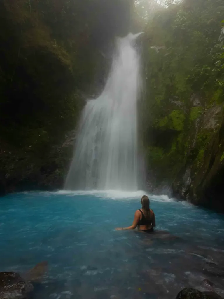 Blue Falls Cataratas Las Gemelas waterfall forming a blue body of water with thick fog surrounded by overgrown rocks and jungle landscape in bajos del toro in costa rica