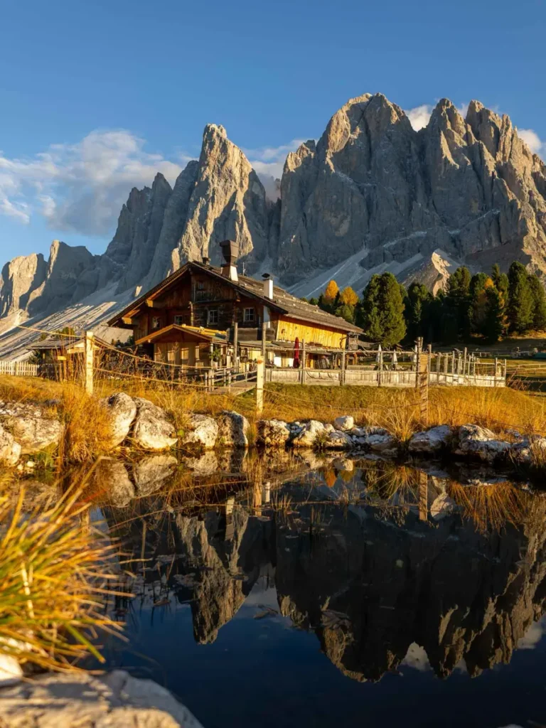 A small pond at Cinema delle Odle, a stunning mountain hut in the Dolomites with majestic mountains in the backdrop reflecting in the water