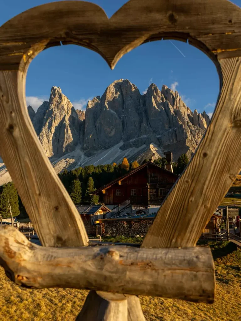 Wooden heart frame revealing a view of a stunning mountain group in the distance at Cinema delle Odle in the Dolomites