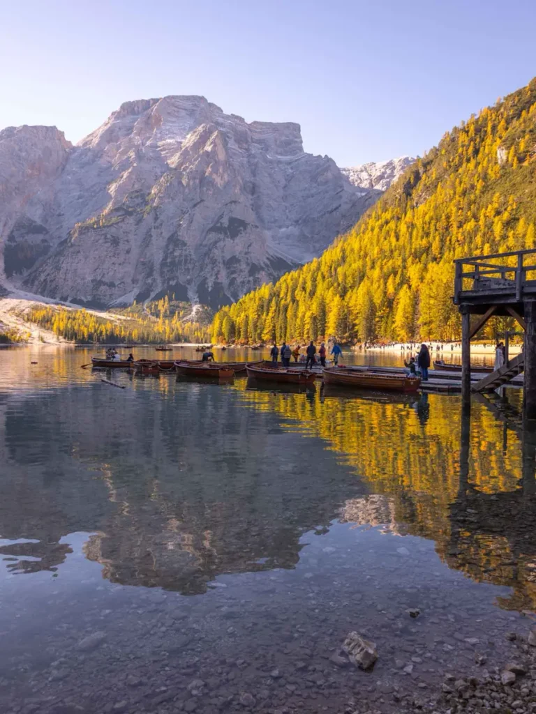 A stunning mountain lake with wooden boats and a wooden platform during autumn in the Dolomites at Lago di Braies