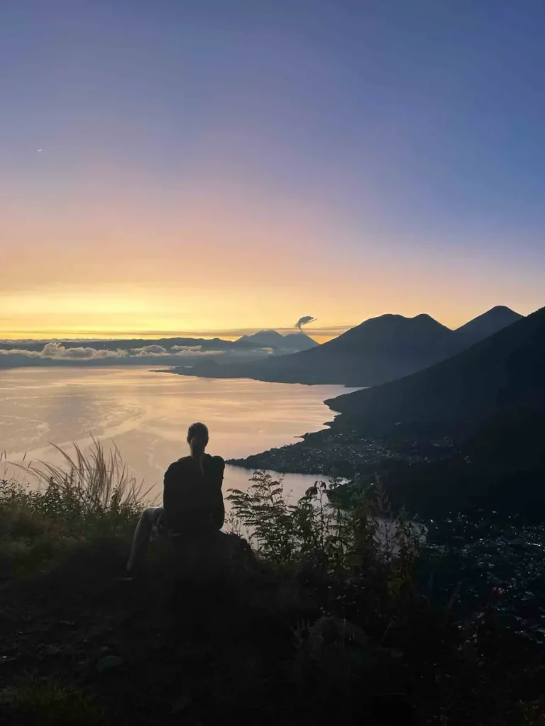 silhouette of a person with a view on lake atitlan and surrounding mountains and volcanoes at indian nose hike at sunrise in guatemala
