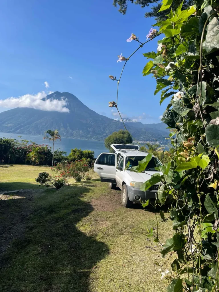 white car camping at Pasaj Cap in San Marcos at lake atitlan in guatemala with greenery and a view on the lake and volcano