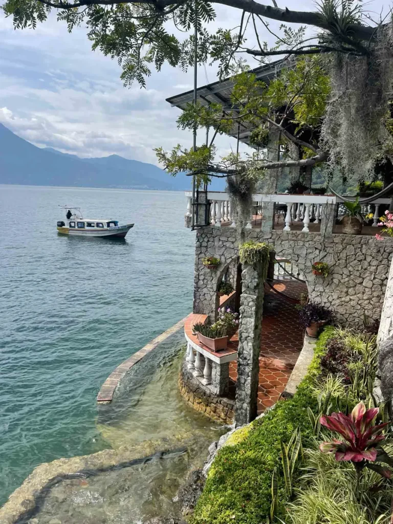 unique terrace and balcony at Casa del Mundo stay at lake atitlan with a boat on the lake and a view on surrounding mountains and volcanoes in guatemala