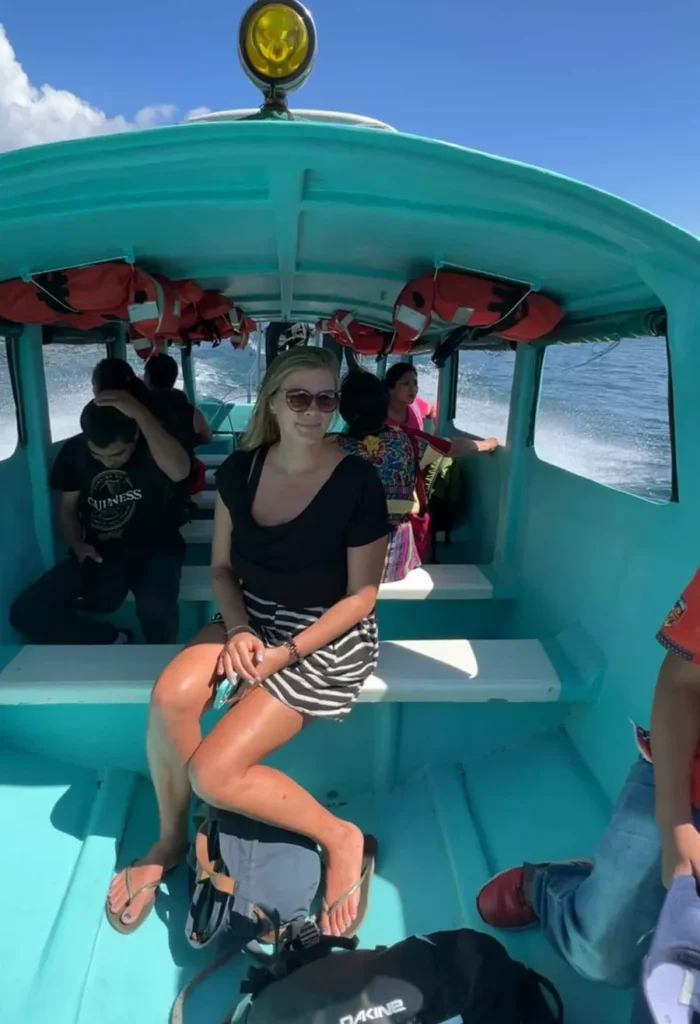 blonde woman sitting in a light turquoise boat, the mean transport at lake atitlan in guatemala