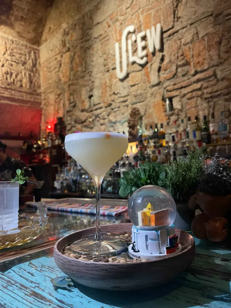 cocktail served in a plate filled with stones and a small snow globe at the traditional cellar style hidden bar ulew