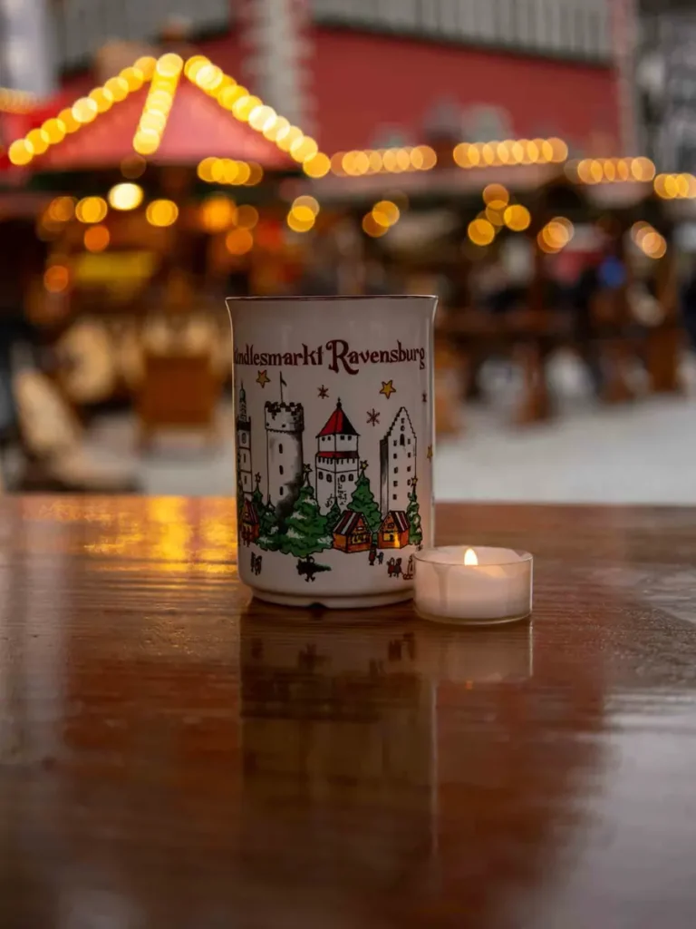 Christmas mug and lit candle standing on a table at one of the most underrated Christmas markets in Germany - Ravensburg