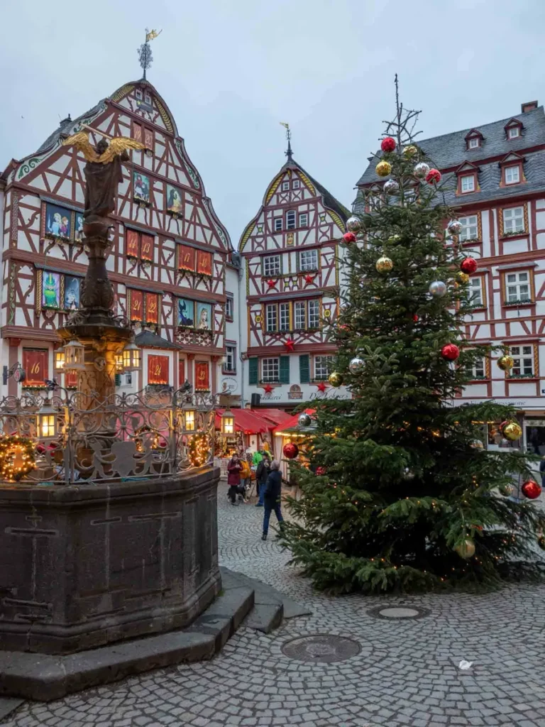 Traditional half-timbered houses around a square with cobblestone roads, a fountain and Christmas decorations in Bernkastel-Küs