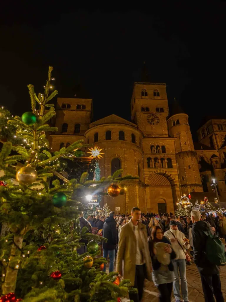 Christmas market with people, stalls and decorations in front of the Trier Cathedral