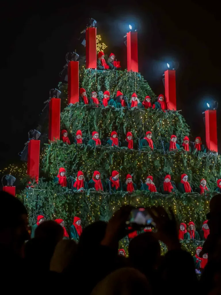 A christmas tree construction with singers in green-red costumes performing a live concert at the Christmas market in Waldkirch, Germany