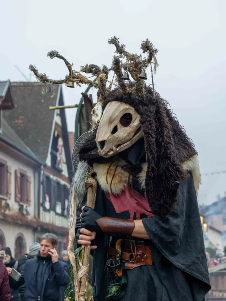 Mythical creature in a costume with antlers, a ceptar and skull mask at the Medieval Christmas market in Ribeavillé